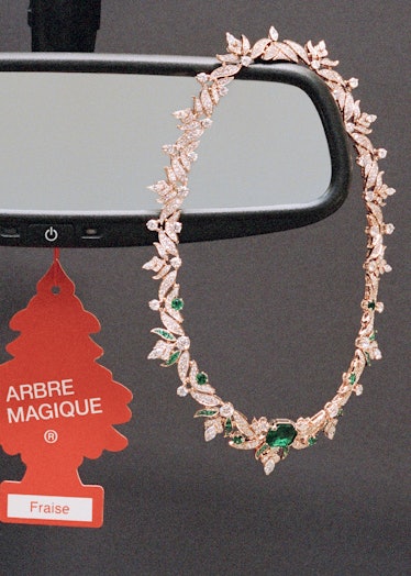 an emerald and diamond necklace dangling from a rear view mirror