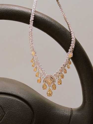 a yellow diamond necklace draped over an old steering wheel