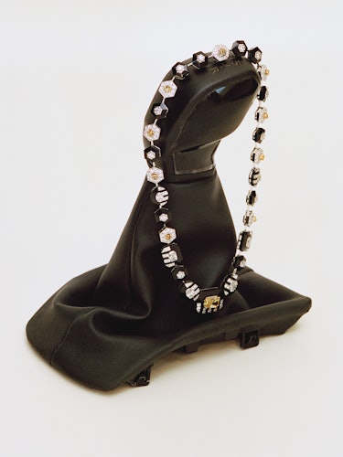 a diamond and sapphire necklace on an old car gear shift