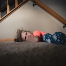 一个倔强的孩子在她家楼梯附近的地毯上撅着嘴。