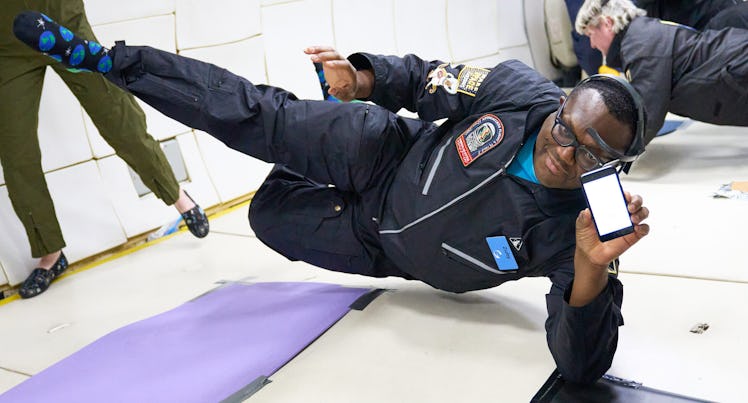 photo of a man floating in microgravity while holding up a smartphone