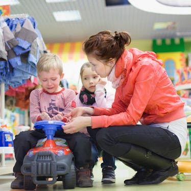 A mother with her two kids in a store while one throws a temper tantrum.