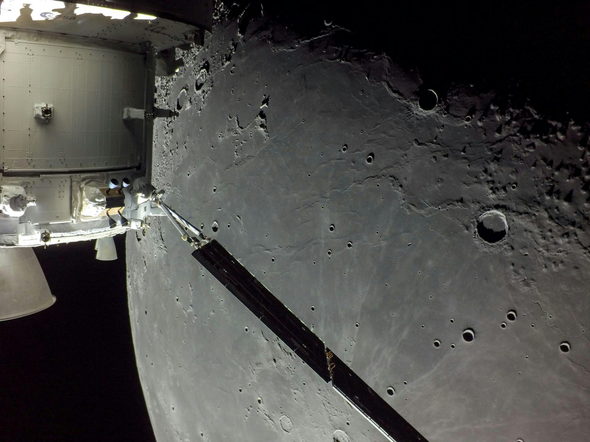 A portion of the far side of the Moon looms large just beyond the Orion spacecraft in this image tak...