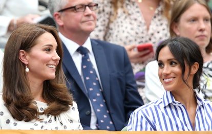 Meghan Markle and Kate Middleton sitting next to each other, smiling