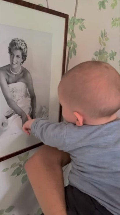 Baby Archie or Lilibet with a picture of Diana Spencer.