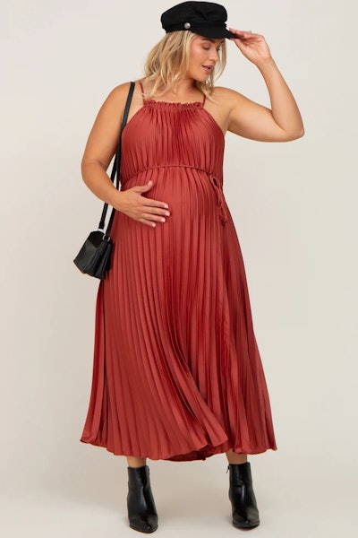 A rust-colored pleated satin dress suited for a maternity New Year's outfit