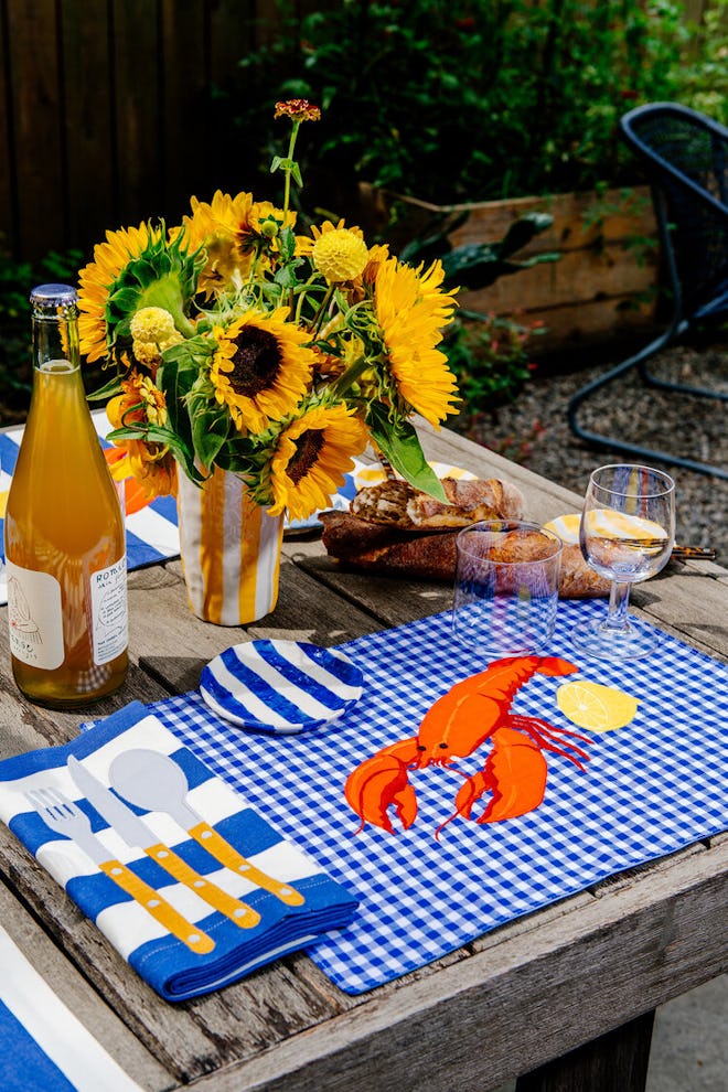 An outdoor dining table with blue gingham lobster placements and matching linens