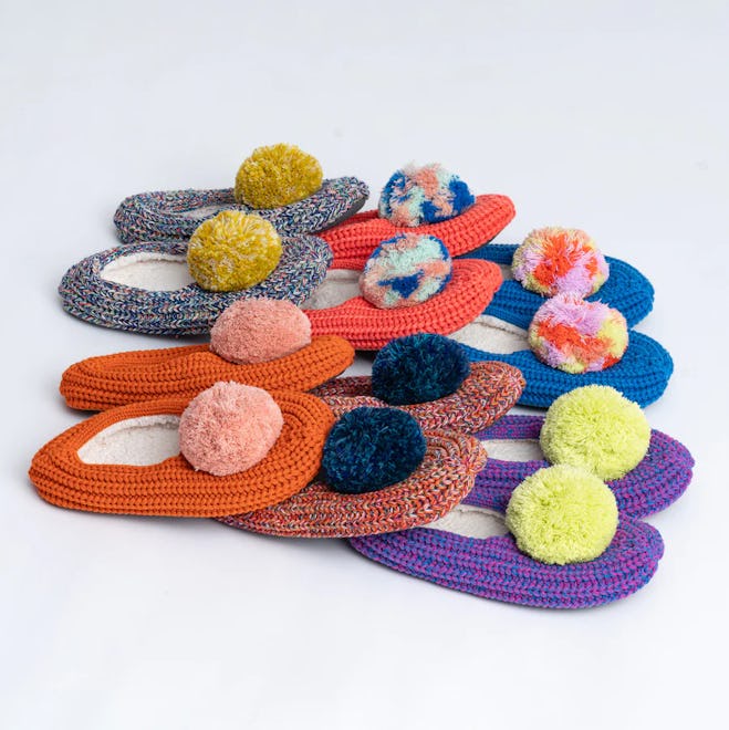 Sock-style knitted slippers with pom poms, all stacked on top of each other