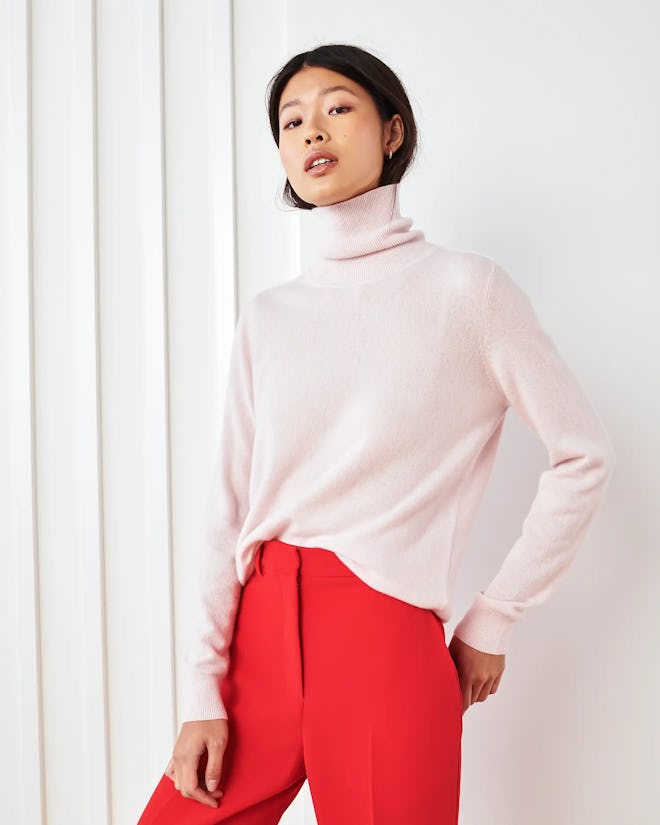 Woman in blush pink cashmere turtleneck sweater and bright red trousers