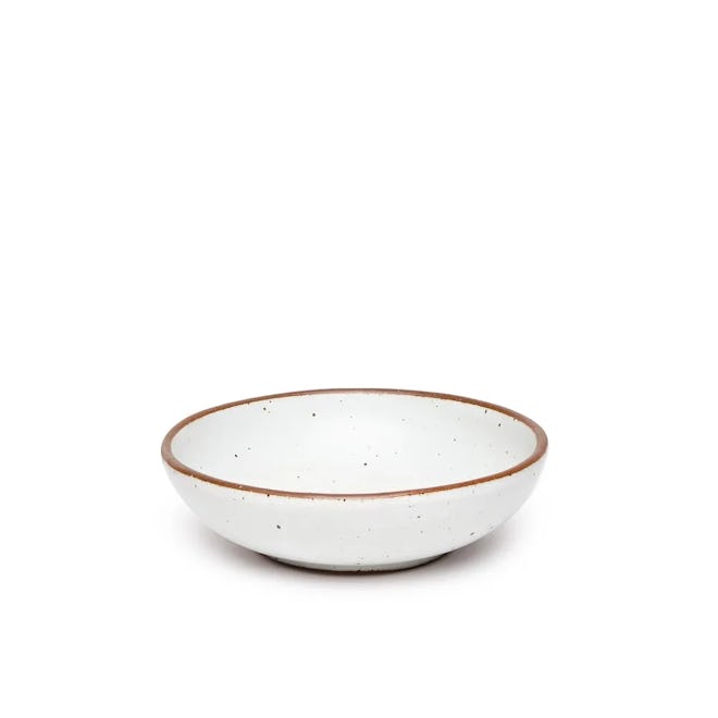 White bowl with black speckle pattern and earthy brown rim