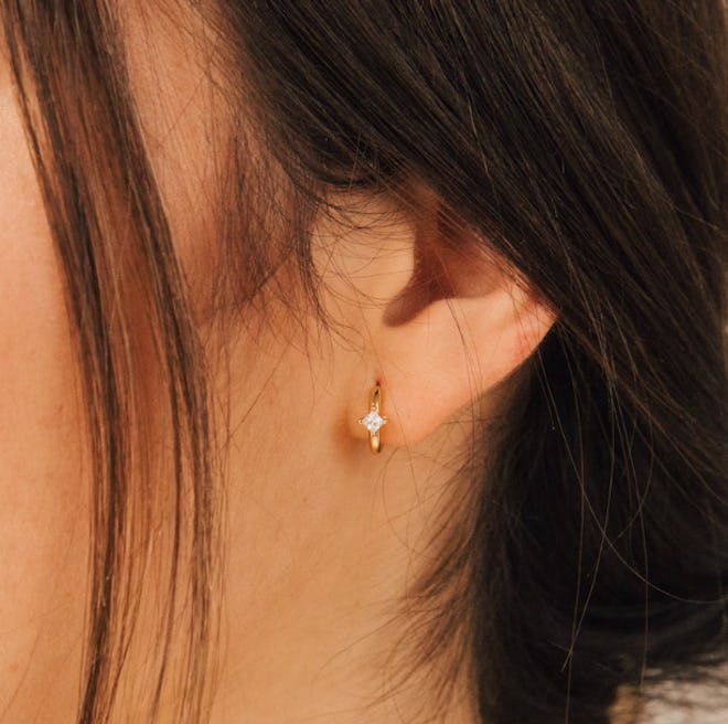 Huggie-style hoop earring, gold, with one small cubic zirconia stone