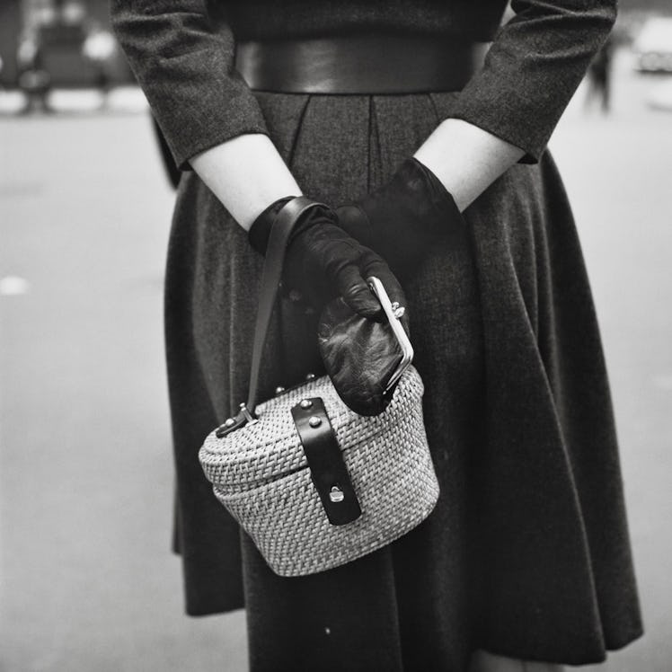 A person holding a basket weave bag and wallet