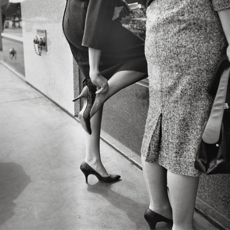 A person adjusting their heels, photographed by Vivian Maier