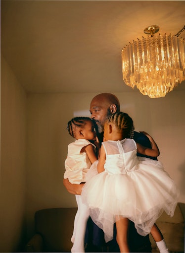man holding two girls in white dresses