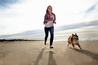 Dog and woman running on the beach