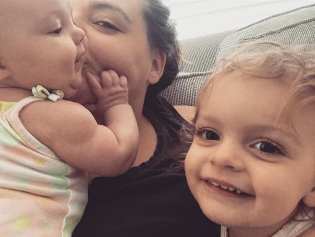 Erica kisses her baby as her toddler smiles at the camera