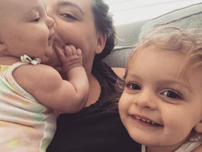 Erica kisses her baby as her toddler smiles at the camera