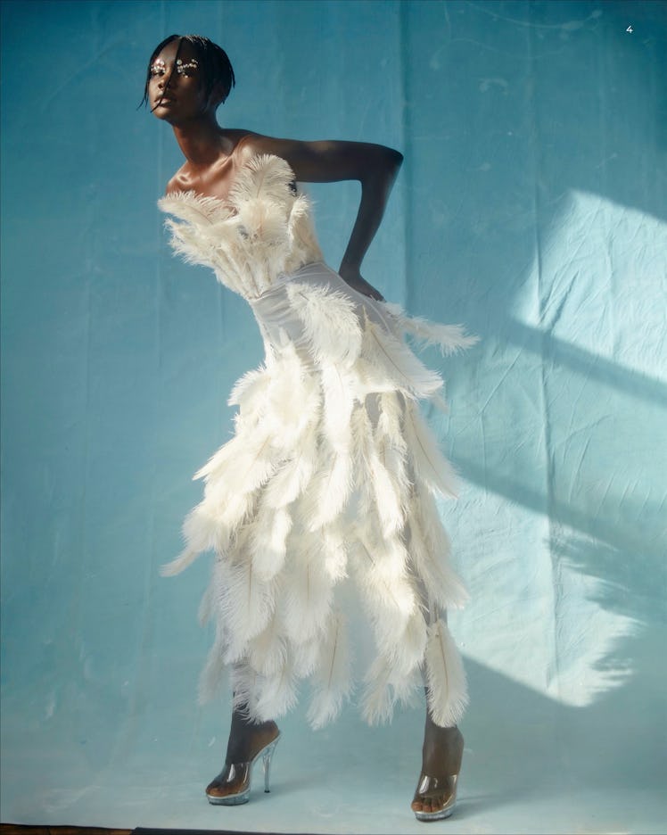 A woman in white feathered dress by Tia Adeola posing