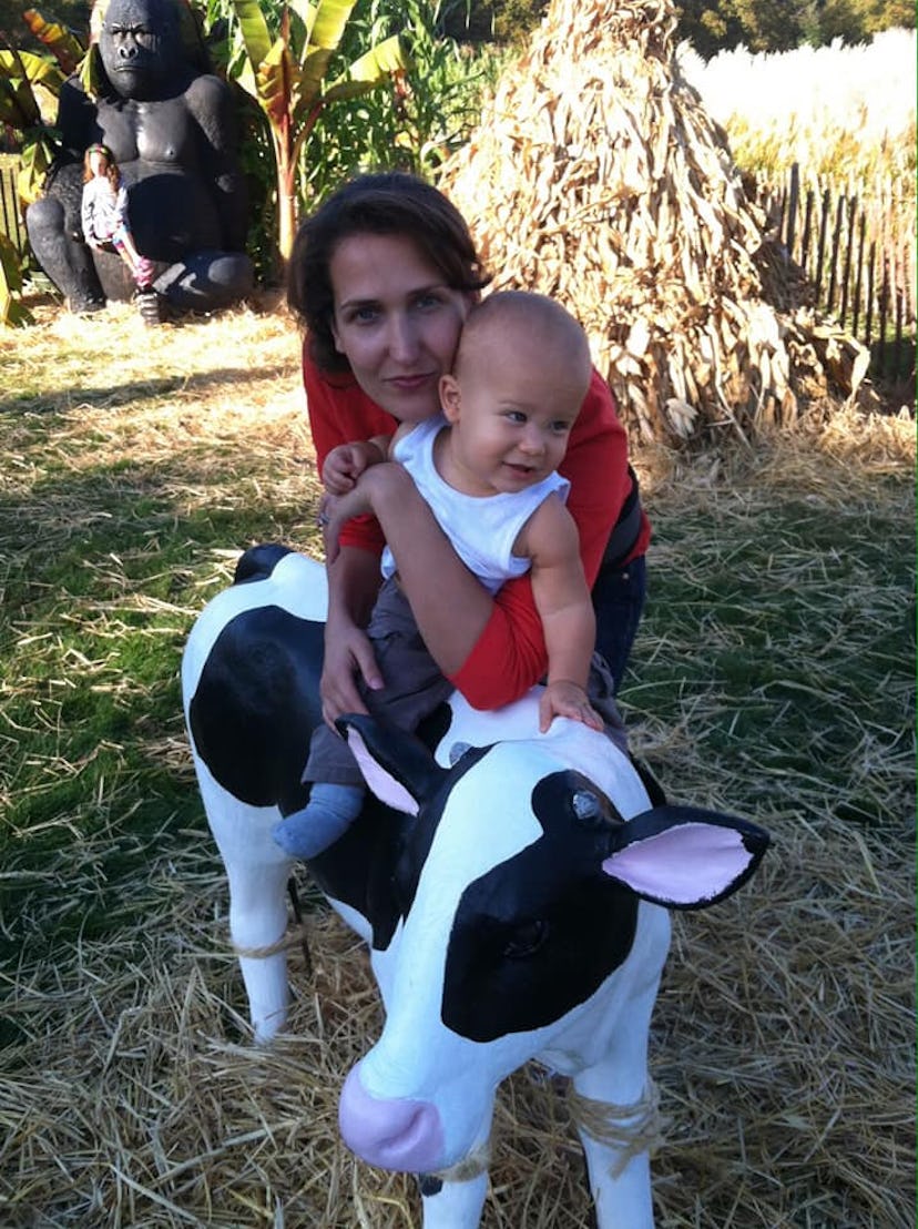 Amanda holds her baby, who sits atop a plaster cow statue.