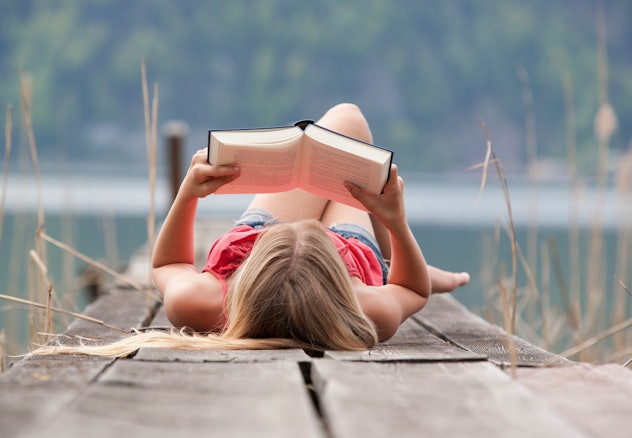 Teenager reading book on a dock 