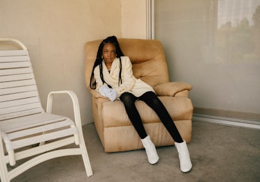 young woman sitting in a leather chair with an ivory jacket on