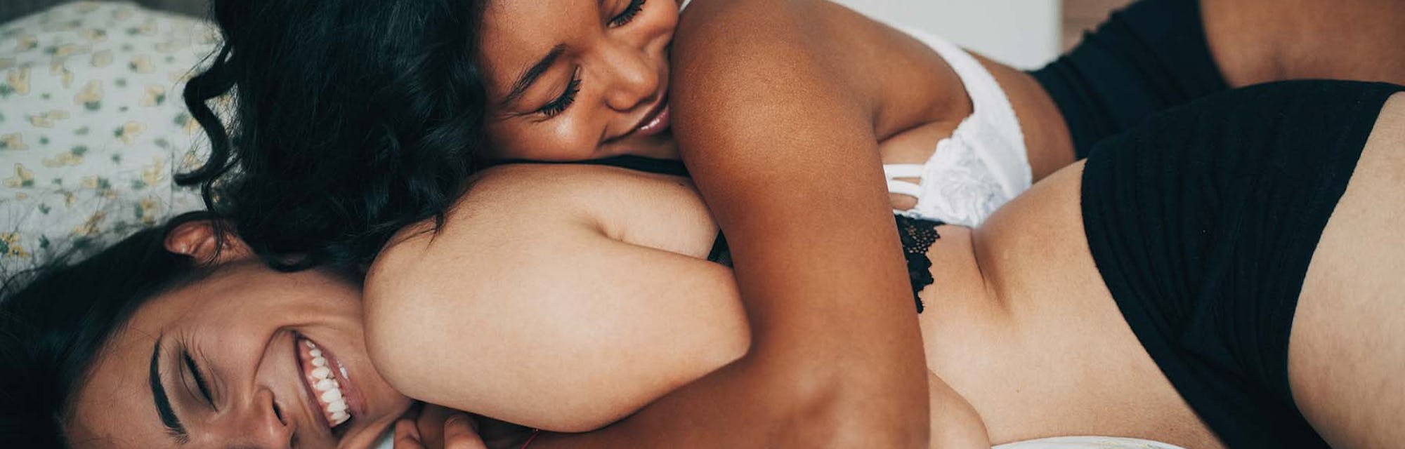 Two women lying in a bed and hugging while trying to get turned on, even though they are exhausted f...