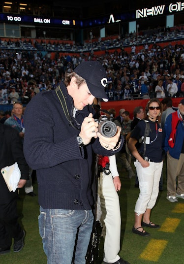 Ashton Kutcher taking a photo at the Super Bowl 