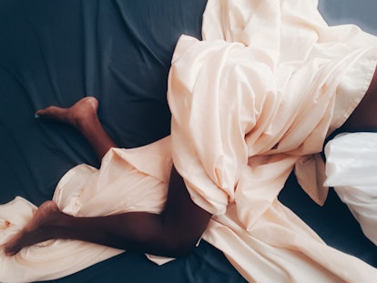 Woman sleeping in bed, tangled up in sheets 