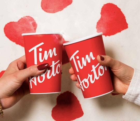 Two people toast with Tim Hortons coffees
