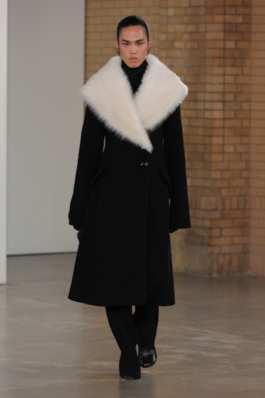 Model on the NY Fashion Week Fall 2022 in Proenza Schouler black coat with a big white furry collar.