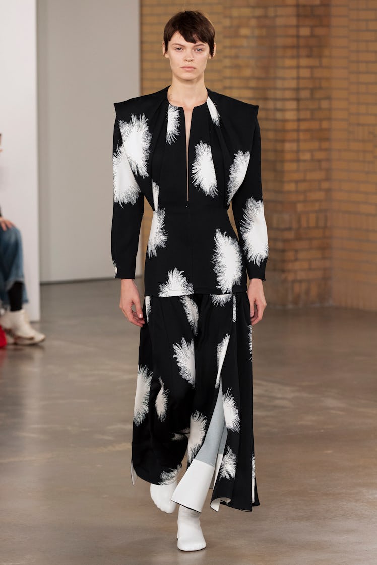 Model on the NY Fashion Week Fall 2022 in Proenza Schouler black wide top and pants with white flowe...