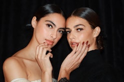 Kendall and Kylie Jenner posing for a photo while holding hands with brown nails on their faces