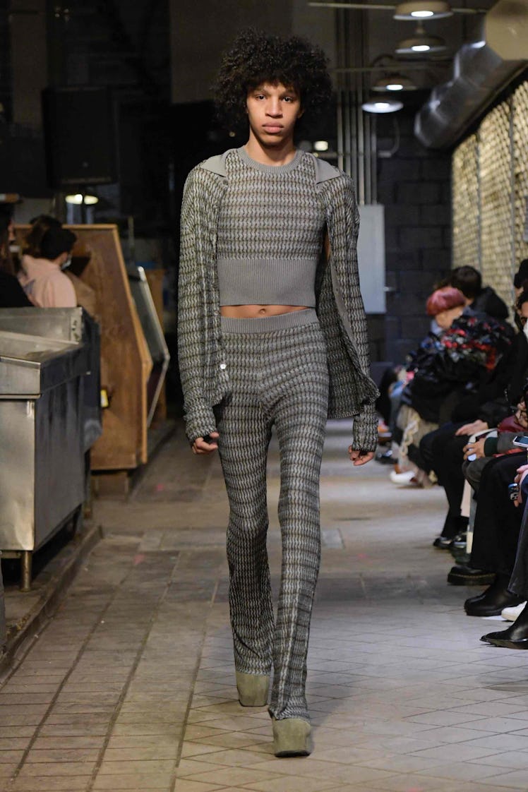 Model on the NY Fashion Week Fall 2022 runway in Eckhaus Latta grey crop top, pants, and a grey swea...