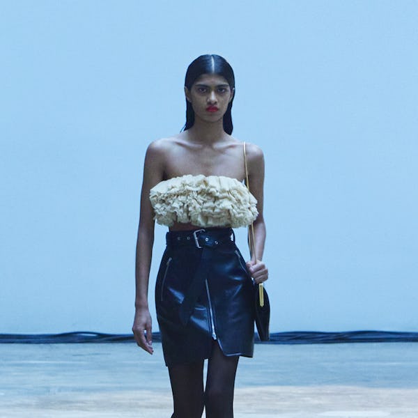 A model wearing a frilled beige top with a black belted mini leather skirt for the Khaite's fashion ...