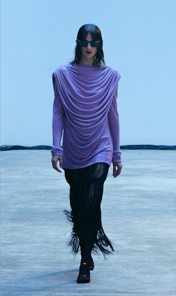 Model walking the Khaite Fall/Winter 2022 runway, wearing a lavender frilled top with black skirt wi...