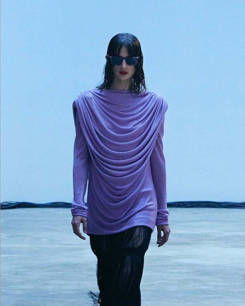 Model walking the Khaite Fall/Winter 2022 runway, wearing a lavender frilled top with black skirt wi...