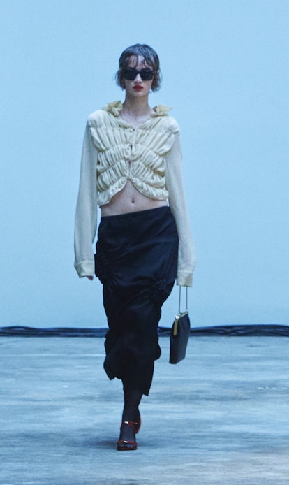A model is wearing a beige ruffled top and a long black skirt from Khaite's Fall/Winter 2022 Collect...