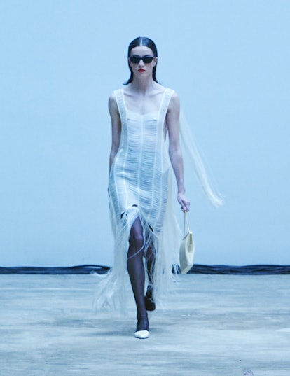 A model walking the Khaite Fall/Winter 2022 fashion show in a white dress.