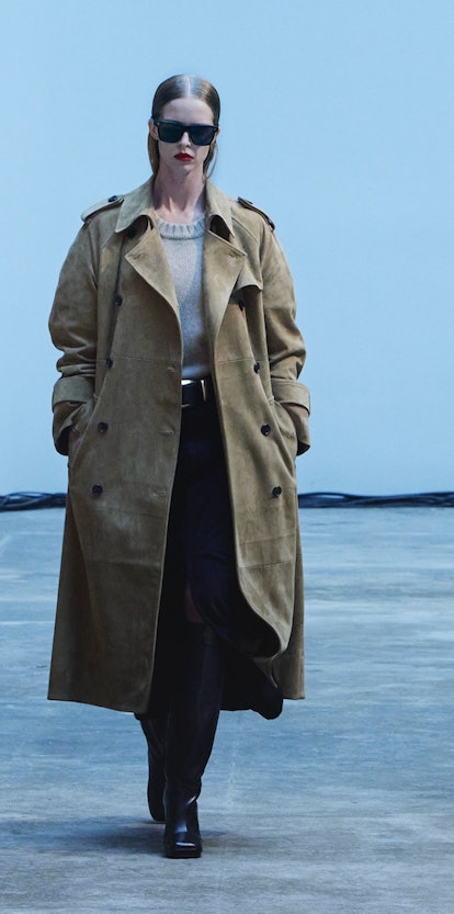 A model walking the Khaite Fall/Winter 2022 show in long light brown leather coat, beige sweater and...