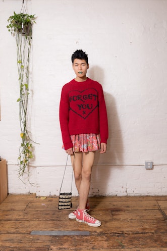 A model wearing a red sweater, pink skirt and Converse shoes from Dauphinette's Fall 2022 collection...