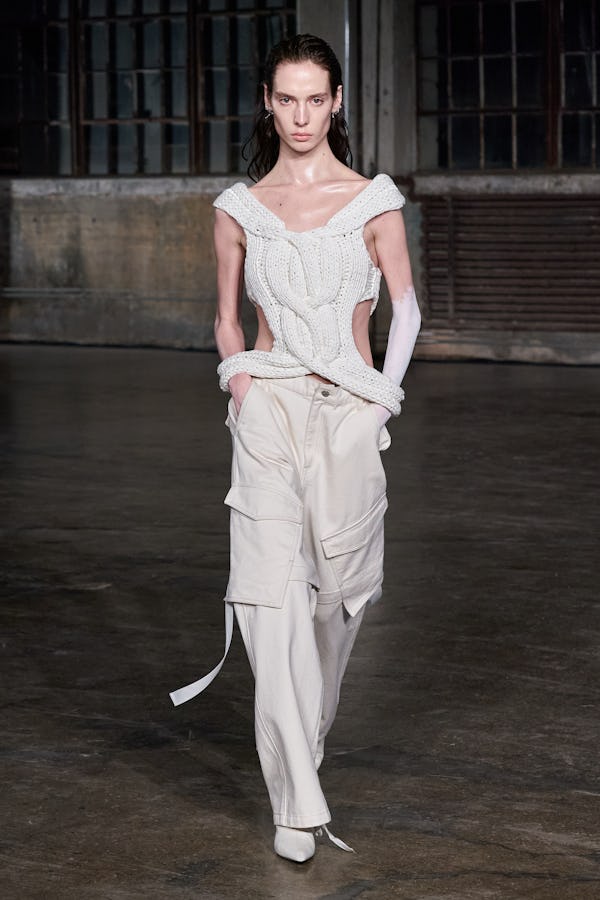 a model wearing an ivory deconstructed cable knit tank and low-slung cargo pants on the Dion Lee run...