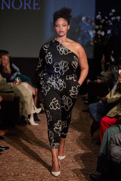 A model wearing a black floral print top and pants on the 11 Honoré runway