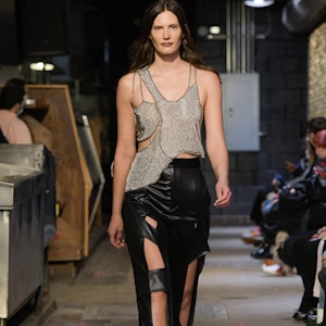 a model wearing a deconstructed metallic tank and black ripped leather pants on the Eckhaus Latta ru...