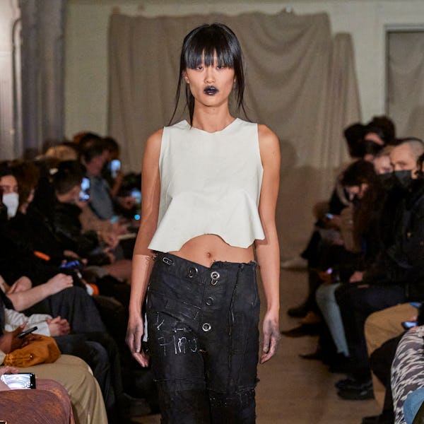 a model wearing a cropped white tank and black low-slung cargo pants on the Elena Velez runway
