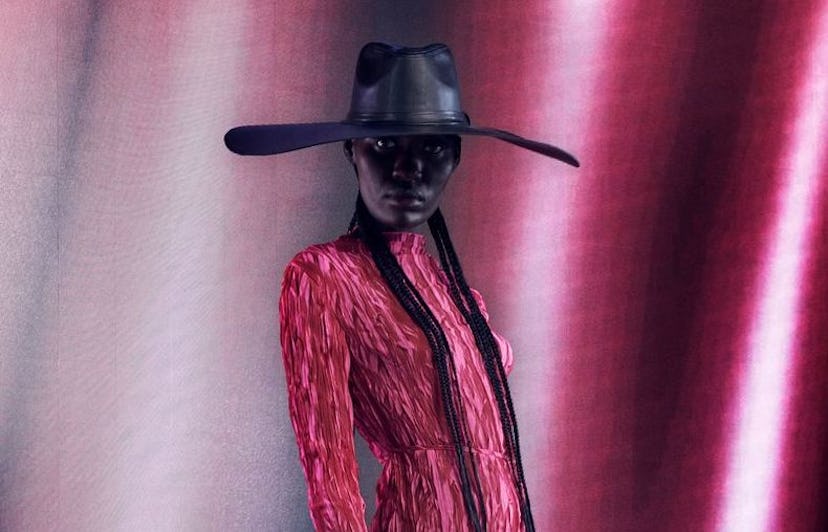 a model in a black hat and pink outfit at NYFW.