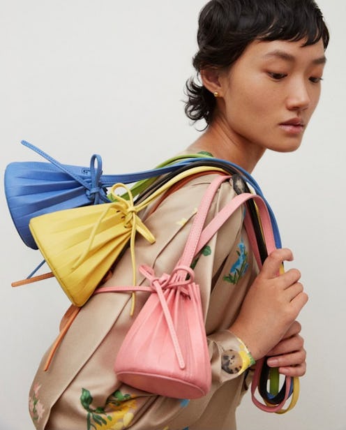 A model posing with Mansur Gavriel's Baby Pleated Bucket Bag. 