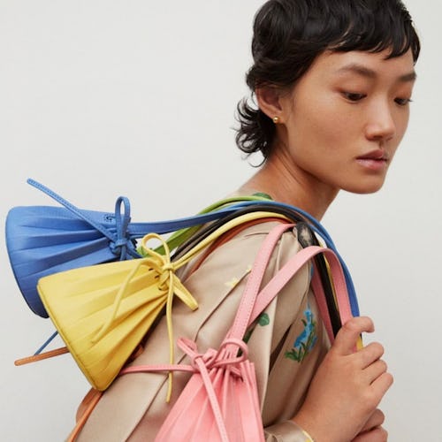 A model posing with Mansur Gavriel's Baby Pleated Bucket Bag. 