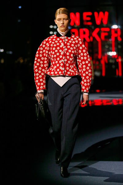 a model wearing a red printed jacket with rounded shoulders on the Tory Burch runway