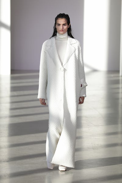 a model wearing a white duster coat on the Bevza runway