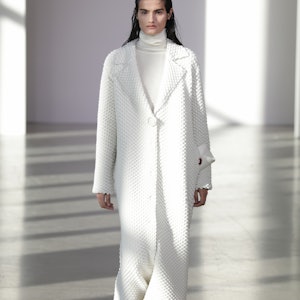 A model in a white duster coat on the Bevza runway